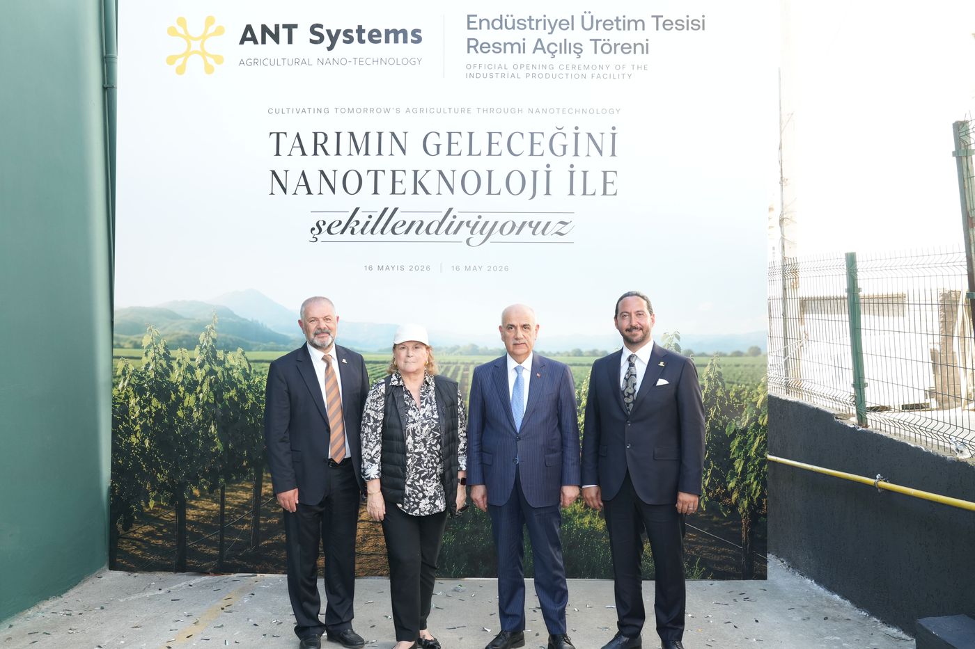 ANT Systems Endüstriyel Üretim Tesisi Resmi Açılış Töreni panosunun önünde yan yana duran dört kişi.