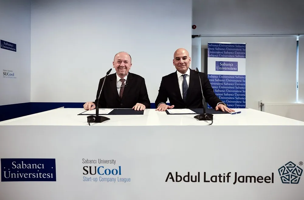 İmza masasında yan yana oturan iki kişi; önlerinde Sabancı Üniversitesi, SUCool ve Abdul Latif Jameel logoları