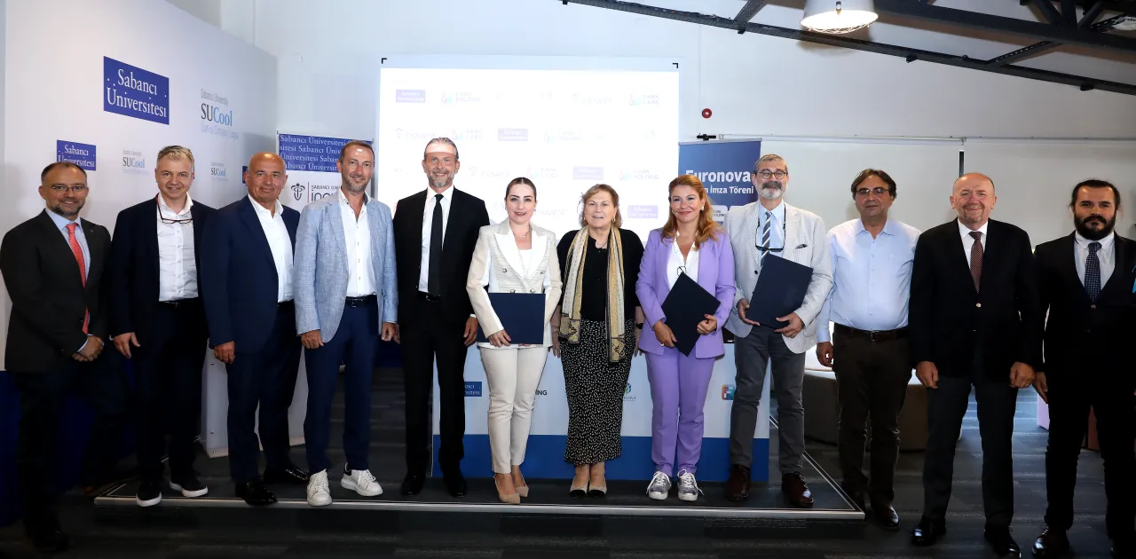 Group photo of thirteen people standing side by side on stage at the Euronova investment signing ceremony.