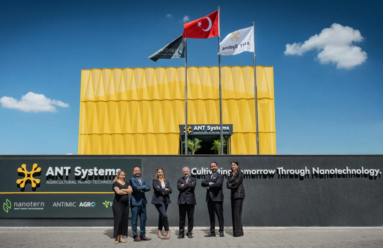 ANT Systems ekibi, sarı cepheli fabrikanın önünde yan yana.